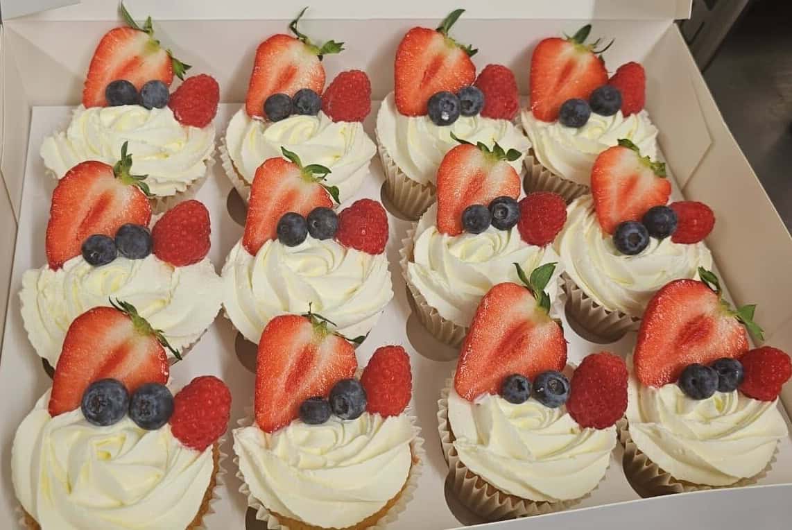 Delicious cupcakes topped with strawberries, blueberries, and raspberries.